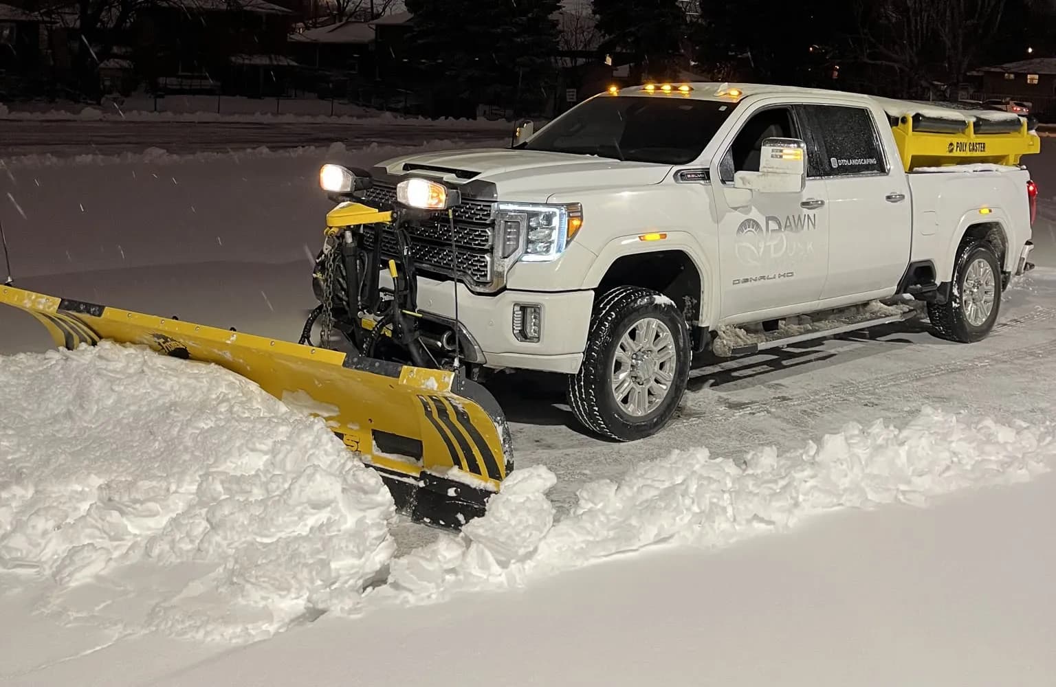 Dawn Till Dusk plow truck clearing a commercial lot during a night snowfall